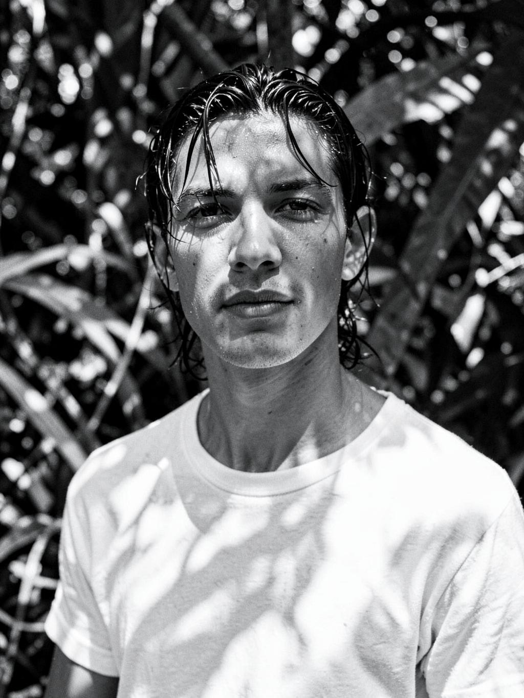 Retrato de un hombre con camiseta blanca entre vegetación tropical