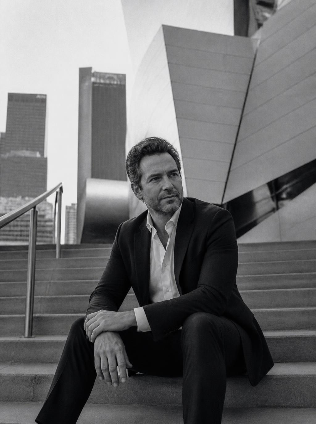 Ejecutivo con traje oscuro sentado en escaleras de arquitectura moderna en Los Ángeles